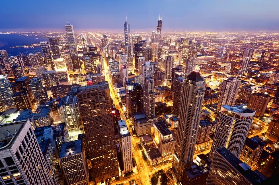 Une photographie nocturne de Chicago, montrant une vue panoramique de la ville avec ses bâtiments hauts et ses rues éclairées.